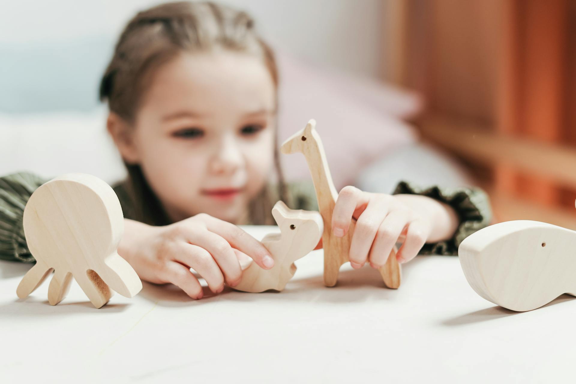 young child plays with white block figures on a white table